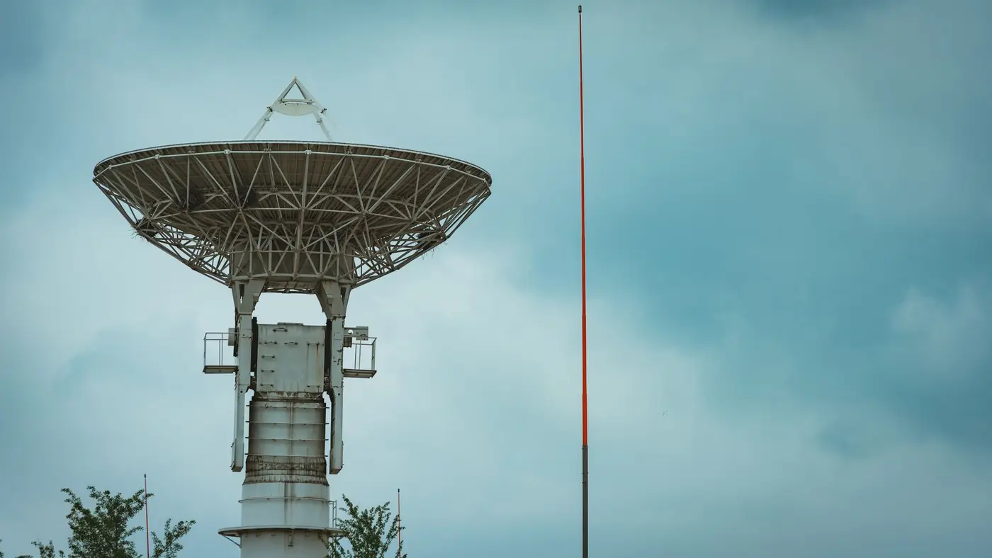 A large satellite dish tower against a cloudy sky