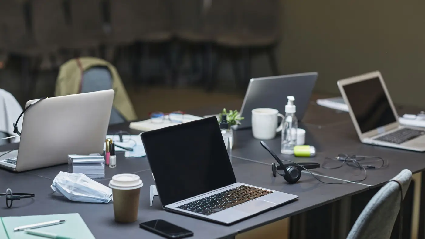 Several laptops open on a shared office desk
